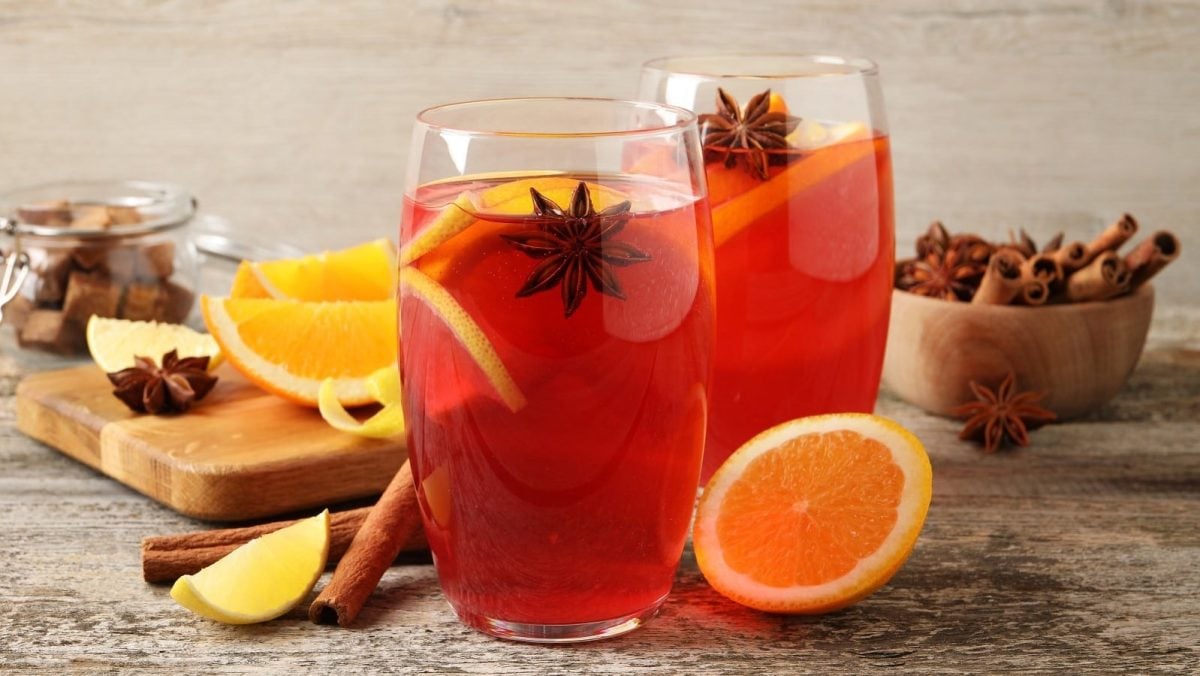 Zwei Gläser mit Hot Mulled Rum neben frischen Zutaten.