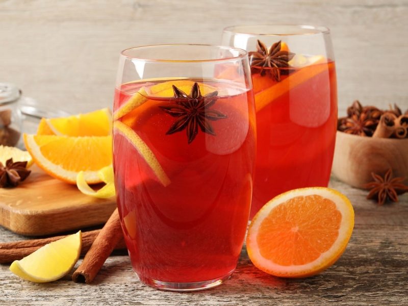 Zwei Gläser mit Hot Mulled Rum neben frischen Zutaten.