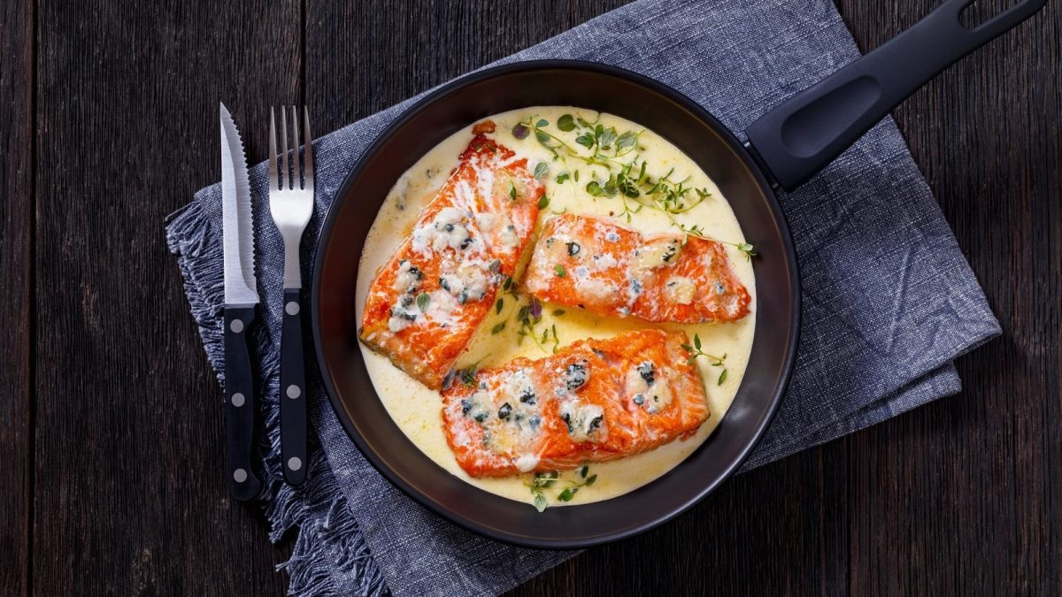Eine Pfanne mit Lachsfilet in Gorgonzolacreme