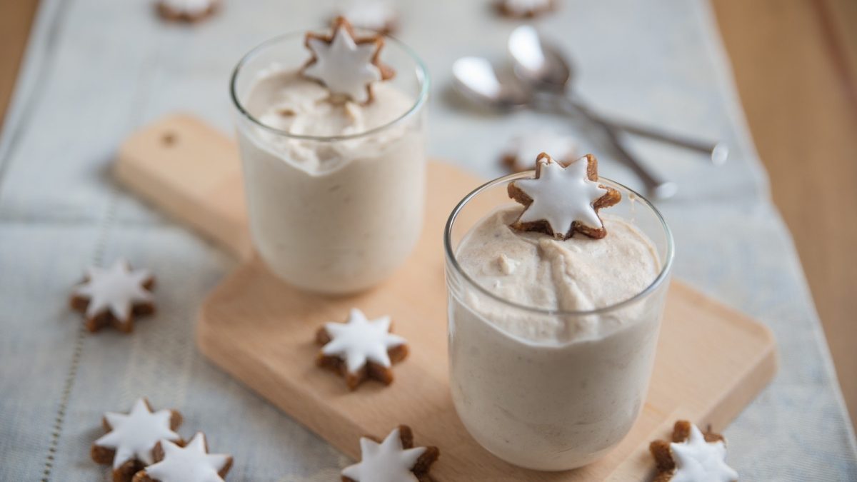Zwei Gläser mit Zimtstern-Creme auf einem Holztablett.
