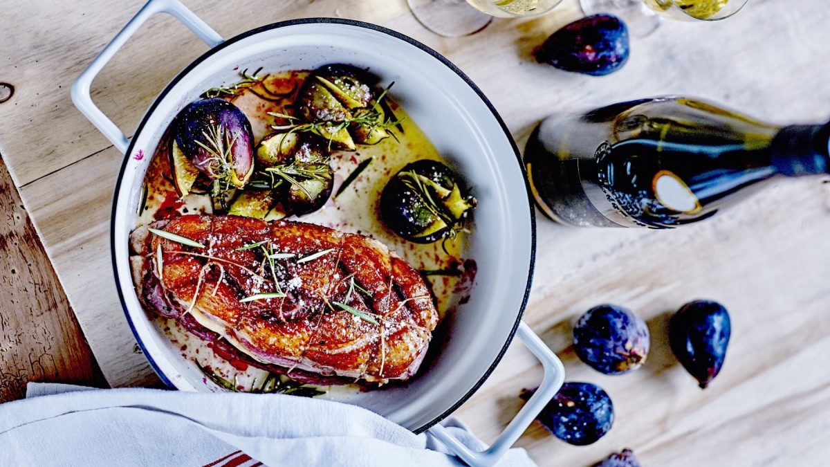 Entenbrust-Cordon-Bleu mit Rosmarin-Feigen im Topf neben Feigen und Weinflasche auf Holz.