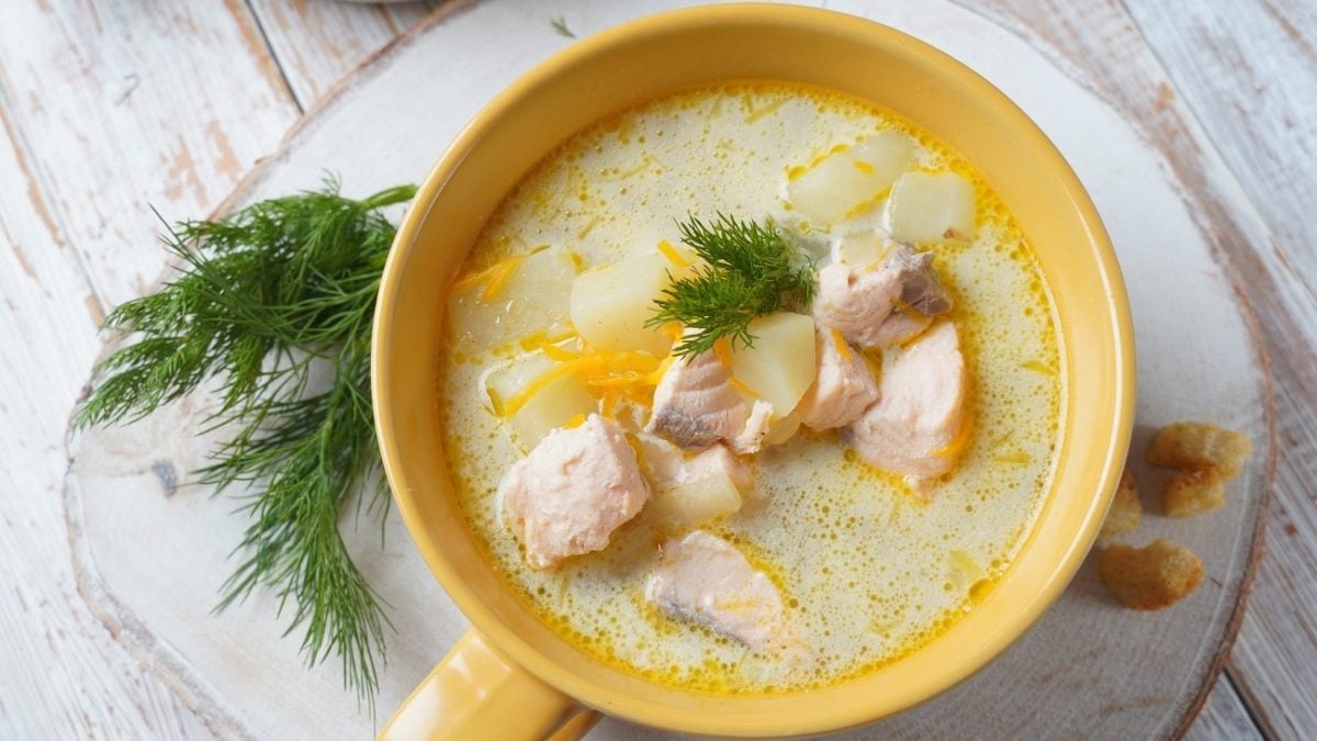 Draufsicht: Auf einem hellen Untergrunf steht eine helle Suppenschale in der eine Fischsuppe angerichtet ist.