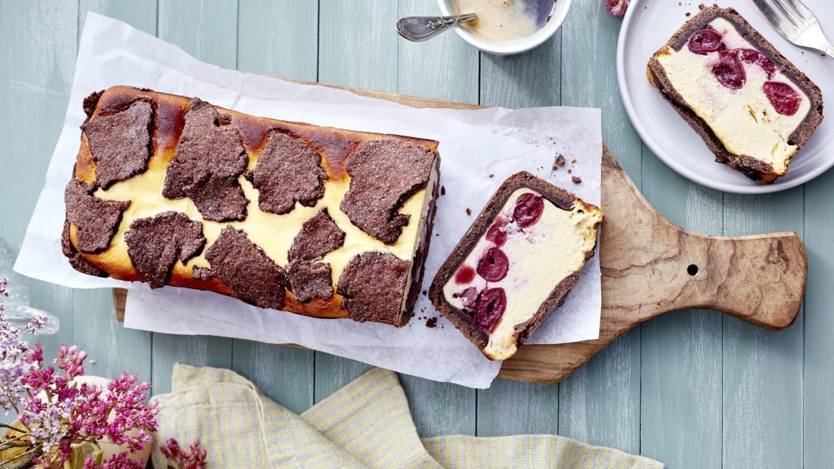 Schwarzwälder Zupfkuchen auf einem Holzbrett in der Draufsicht, daneben ein Teller mit einem Stück davon.