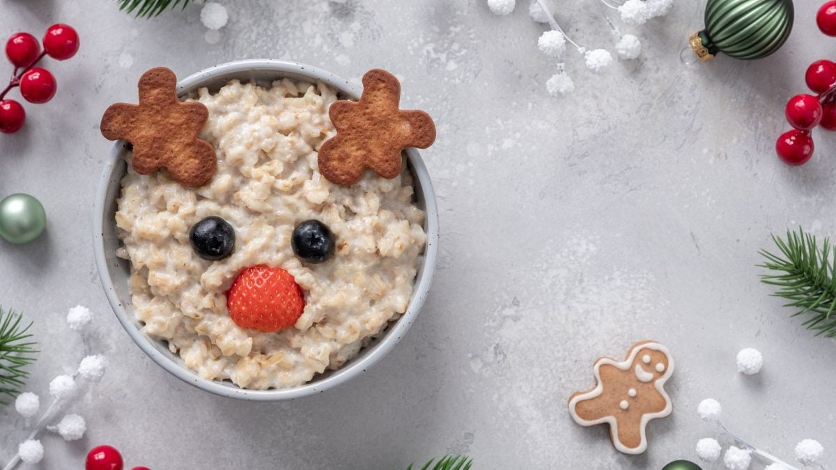 Eine Schale Spekulatius-Porridge mit einem Gesicht aus Beeren und Keksen. Draufsicht.