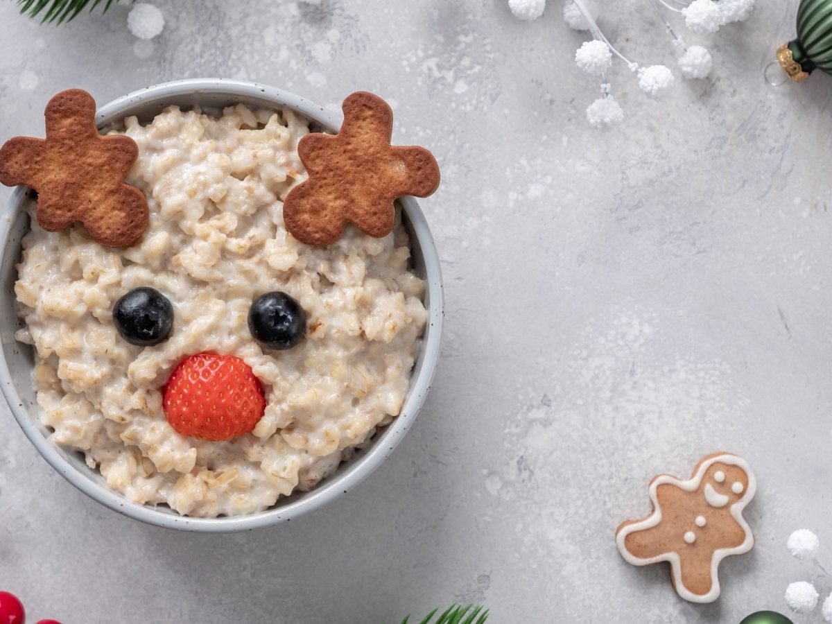 Eine Schale Spekulatius-Porridge mit einem Gesicht aus Beeren und Keksen. Draufsicht.
