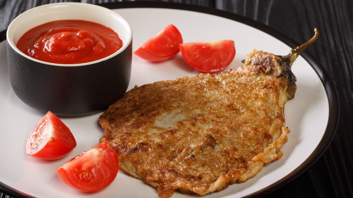 Tortang Talong philippinisches Auberginen-Omelett mit Tomaten und einer Schale Ketchup auf weißem Teller. Draufsicht.