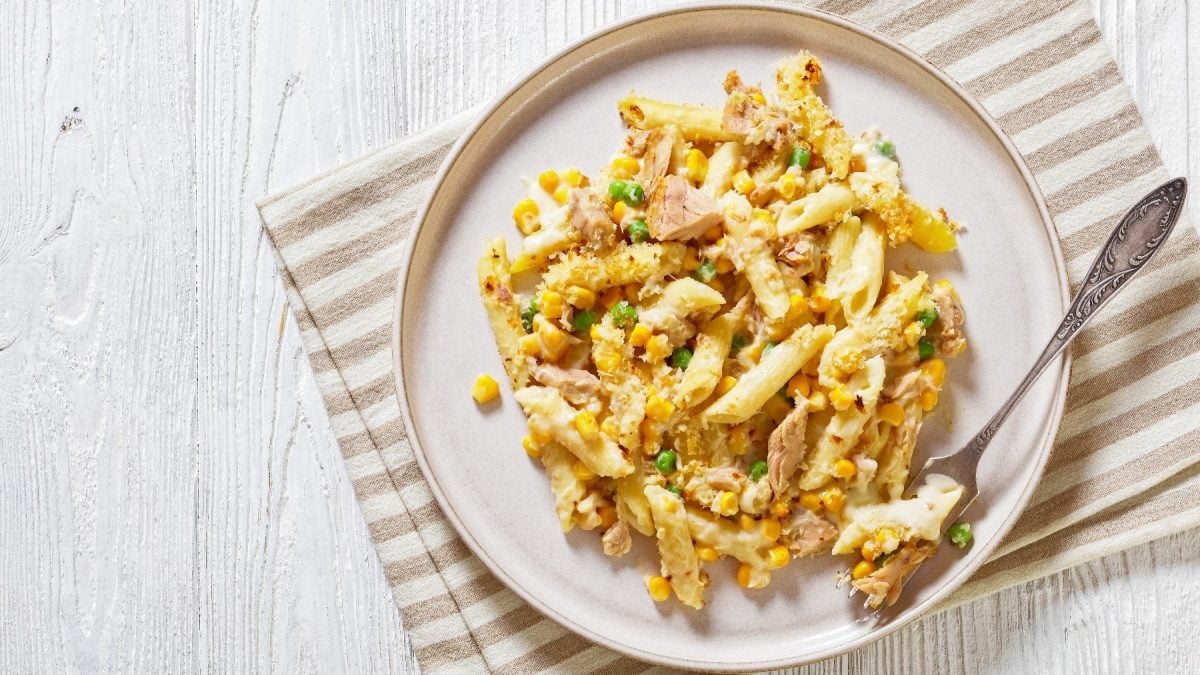 Ein weißer Teller auf einem hellen Holz-Untergrund mit der Thunfisch-Pasta.