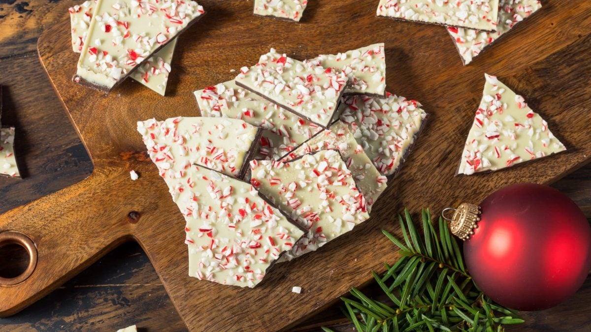 Die weihnachtliche Bruchschokolade auf einem dunklen Holzbrett mit weihnachtlicher Dekoration.