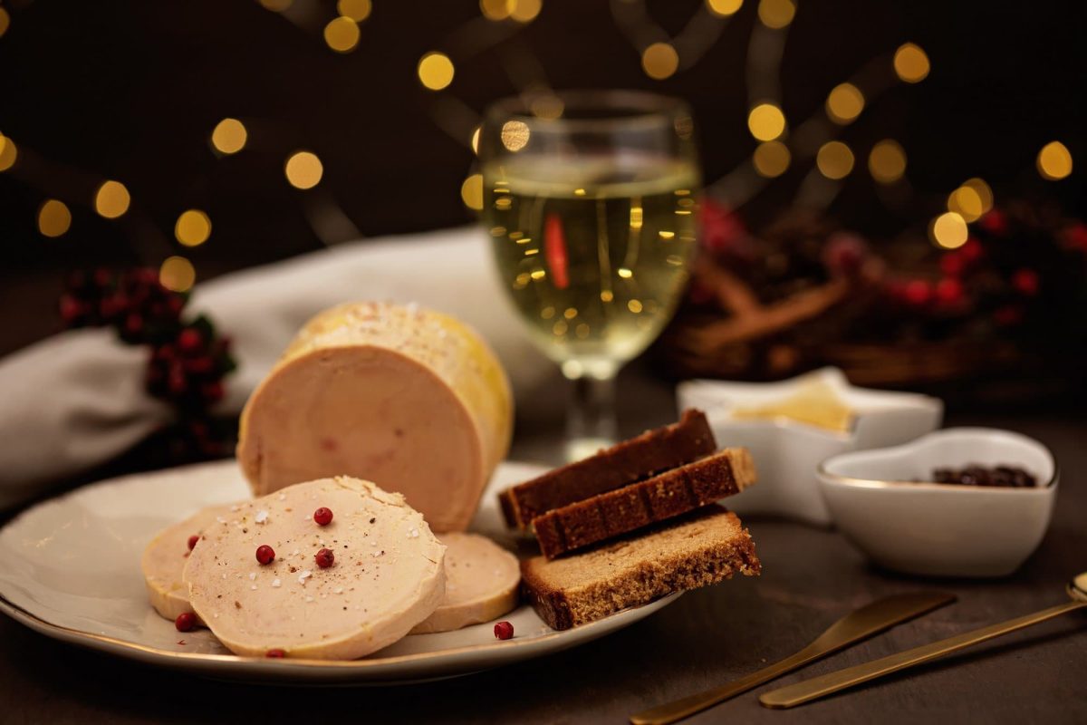 Weihnachtsessen in Frankreich, ein gedeckter Tisch mit einem Weinglas und Foie Gras und weiteren Kleinigkeiten.