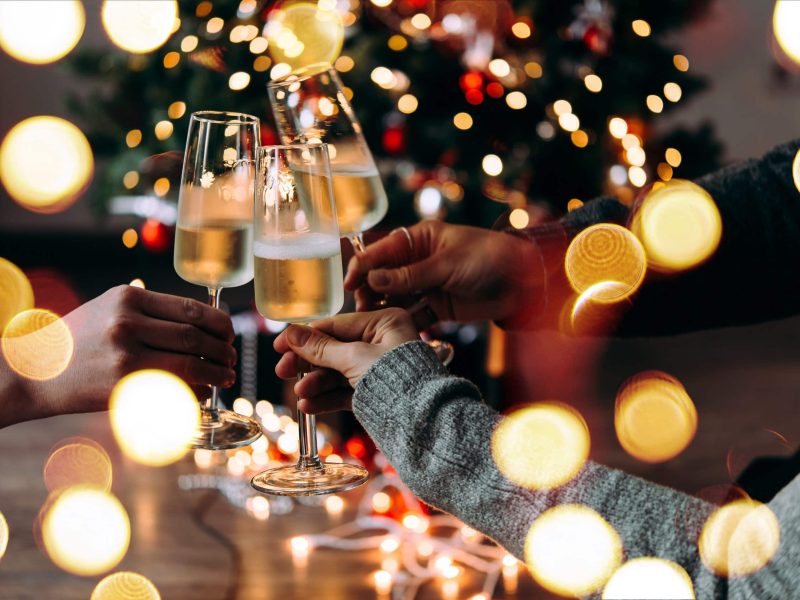 Weihnachtsgetränke: Ein paar Hände, die mit Sektgläsern anstoßen.