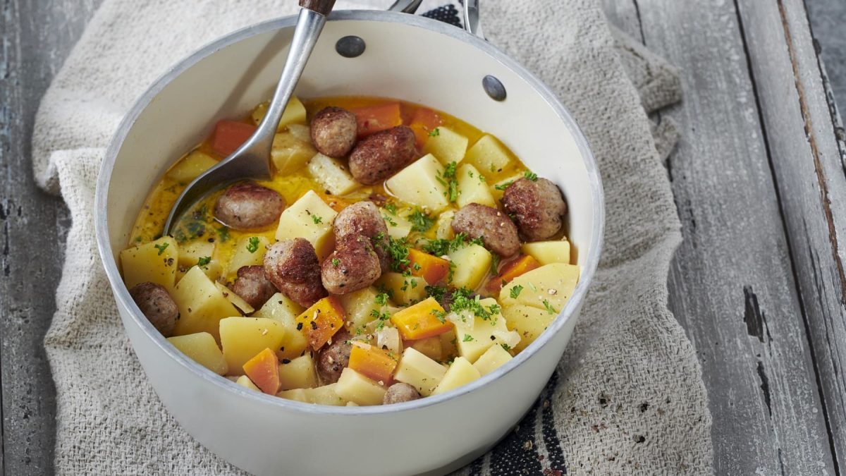 Pastinaken-Kartoffeltopf mit Hackbällchen, serviert in einer großen Schale und garniert mit frischer Petersilie.