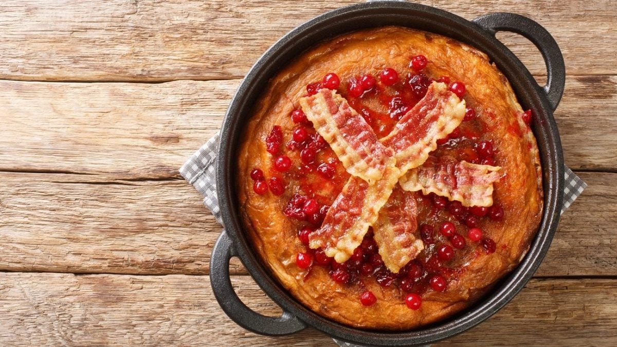 Draufsicht: Eine schwarze Pfanne mit einem schwedischen Pfannkuchen steht auf einem Holztisch.