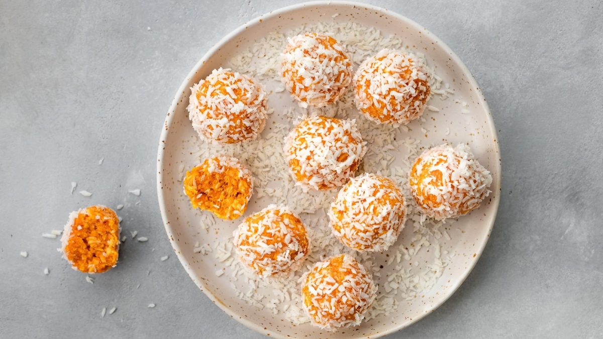 Mehrere der Aprikosen-Bällchen auf einem weißen Teller und grauem Untergrund.