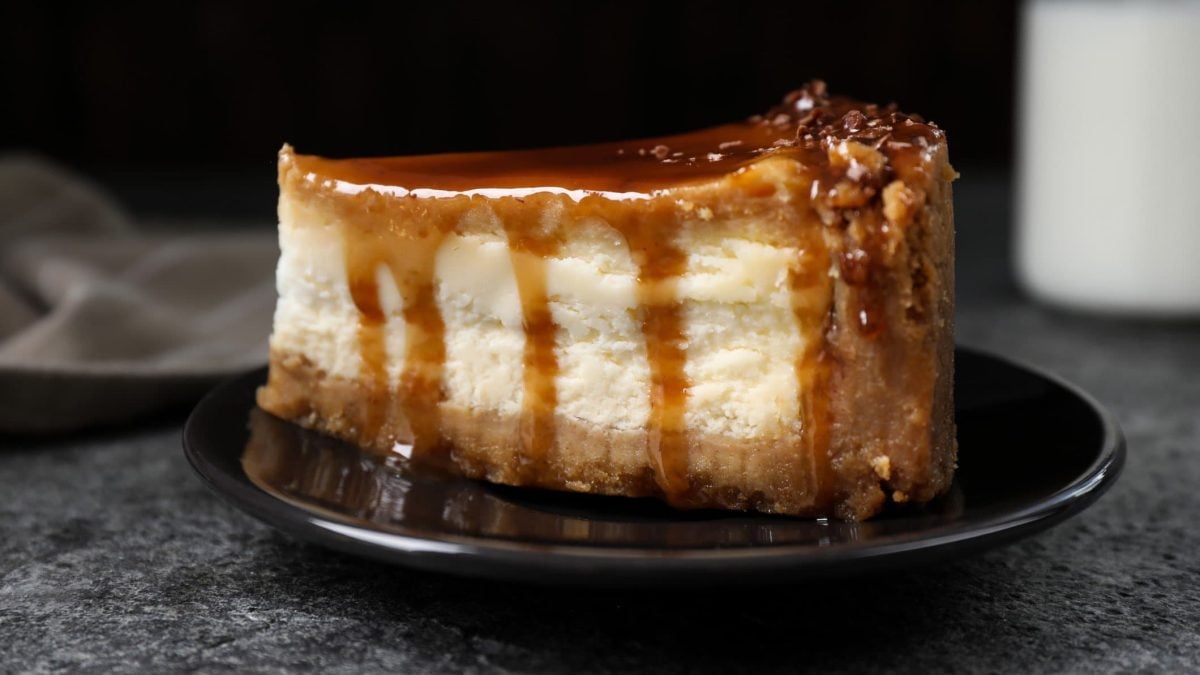 Ein Stück vom Brezel-Cheesecake auf einem schwarzen Teller und grauem Untergrund.