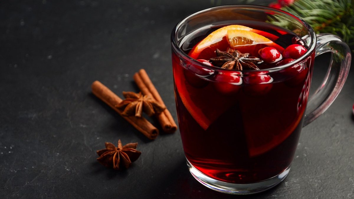 Ein Teeglas Cranberry Hot Toddy mit Orangenscheiben, Anis unc Cranberrys.