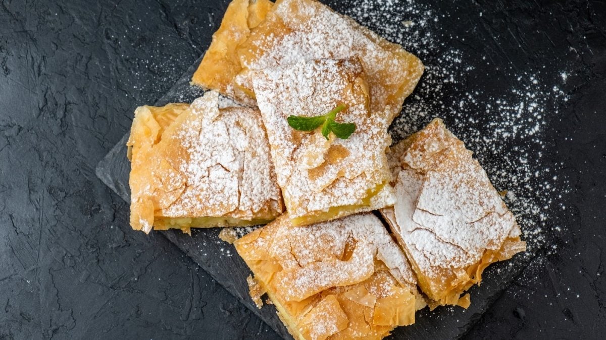 Mehrere Stücke Bougatsa auf einer schwarzen Schieferplatte