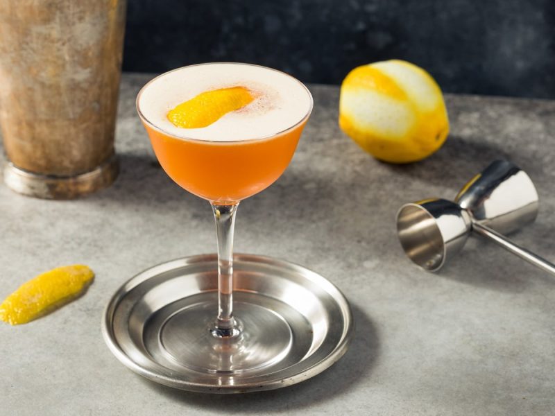 Ein Glas mit Earl Grey Martini neben frischen Zitronen.