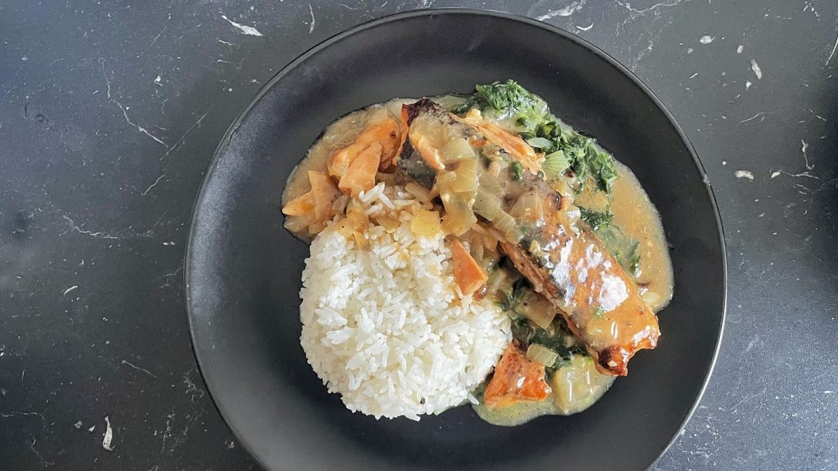 Ein schwarzer Teller mit Lachs auf Kokos-Spinatbett