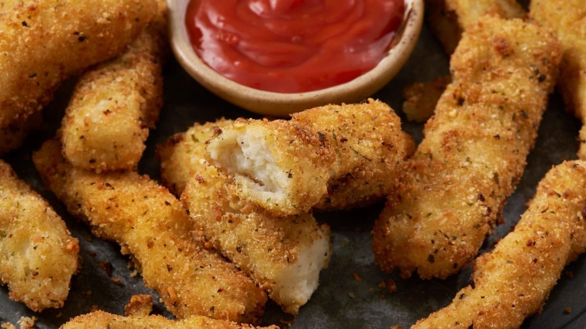 Mashed Potato Fries auf einem Holzbrett neben Ketchup.