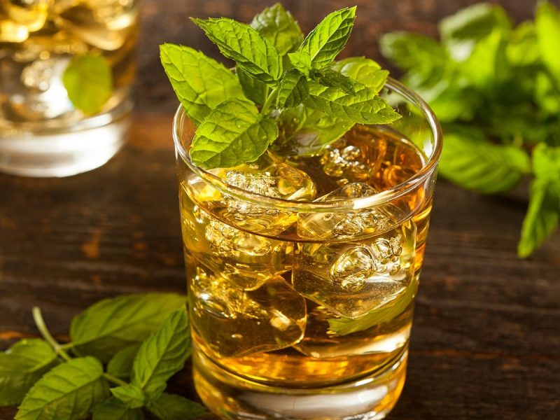 Ein Glas mit Winter Julep auf einem Holztisch.