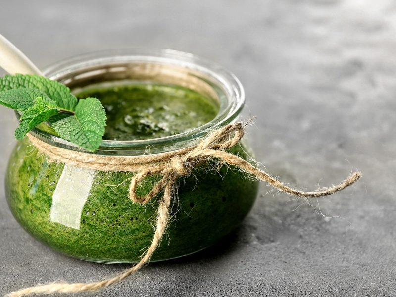 Ein Glas mit Minz-Pesto auf einem grauen Tisch.