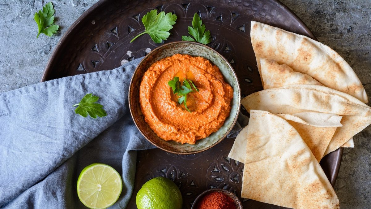 Eine kleine Schale mit Muhammara auf einem schwarzen Teller.