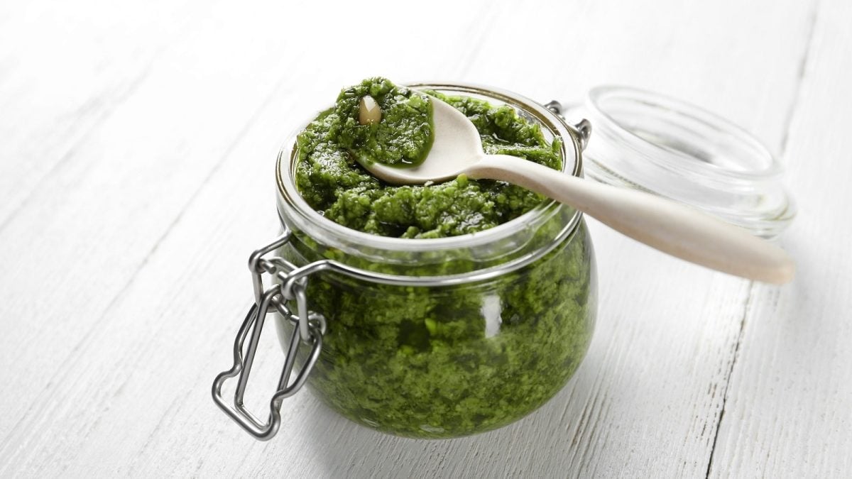 Ein Glas mit Rosenkohl-Pesto auf einem weißen Holztisch.