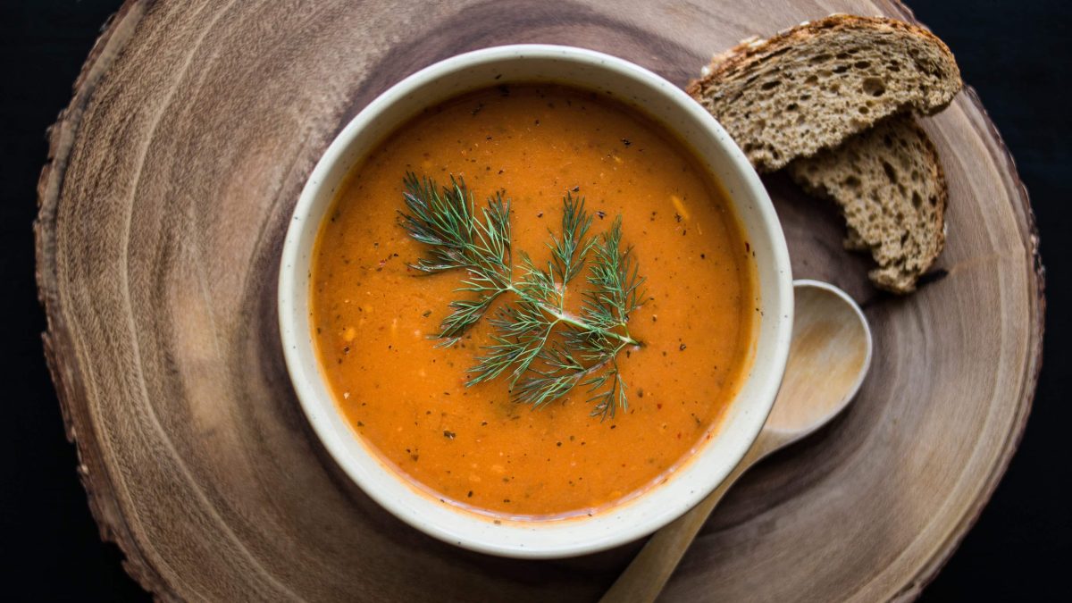 Eine Holzplatte mit Tarhana-Suppe und Brot.