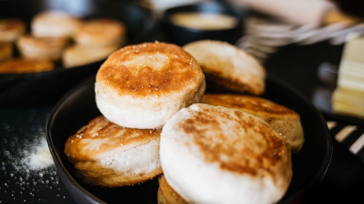 Mehrere English Muffins in einer schwarzen Pfanne mit unscharfem Hintergrund.