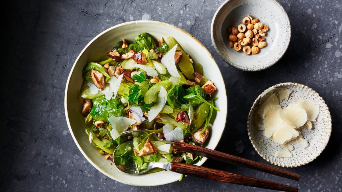 Eine weiße Schale mit dem grünen Salat und Haselnussdressing.