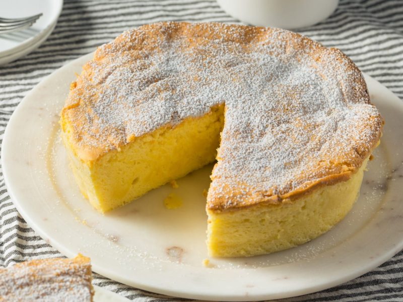 Japanischer Soufflé Käsekuchen mit Puderzucker angeschnitten auf einem weißen Teller.
