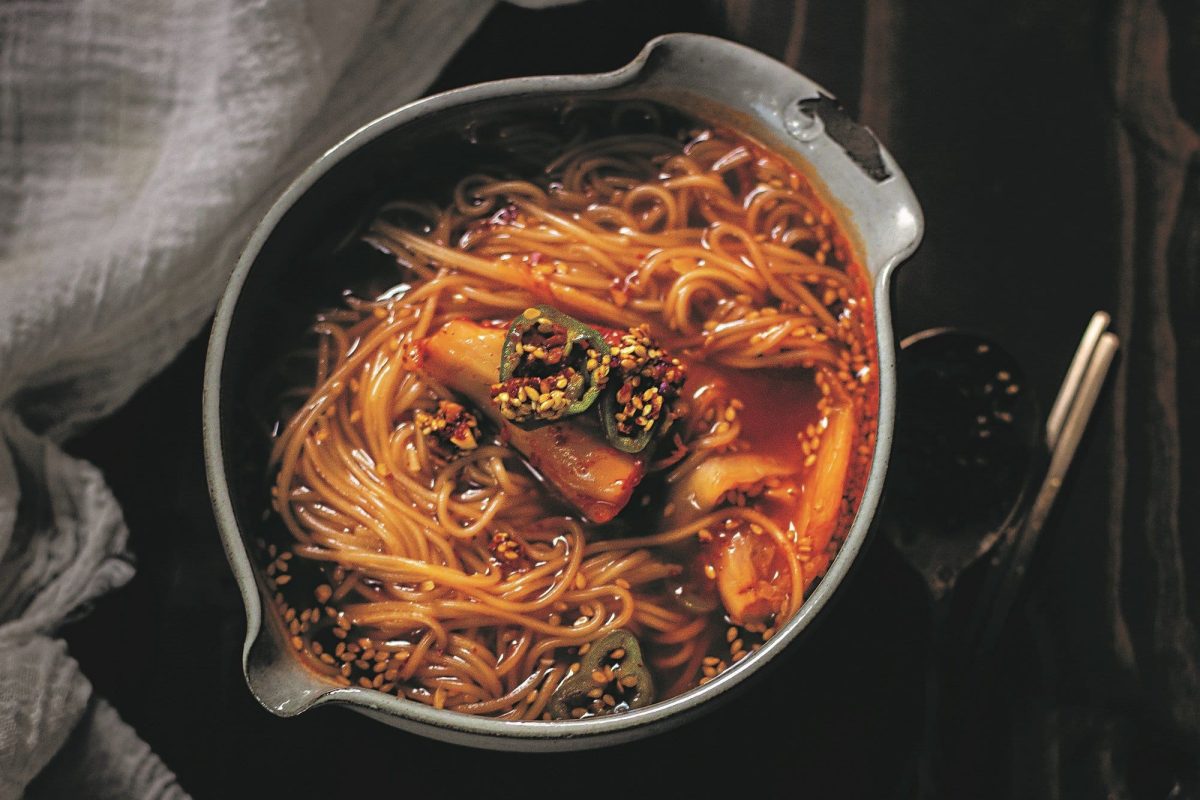 Ein Topf Kimchi-Nudeln mit grünen Chilis in der Draufsicht.