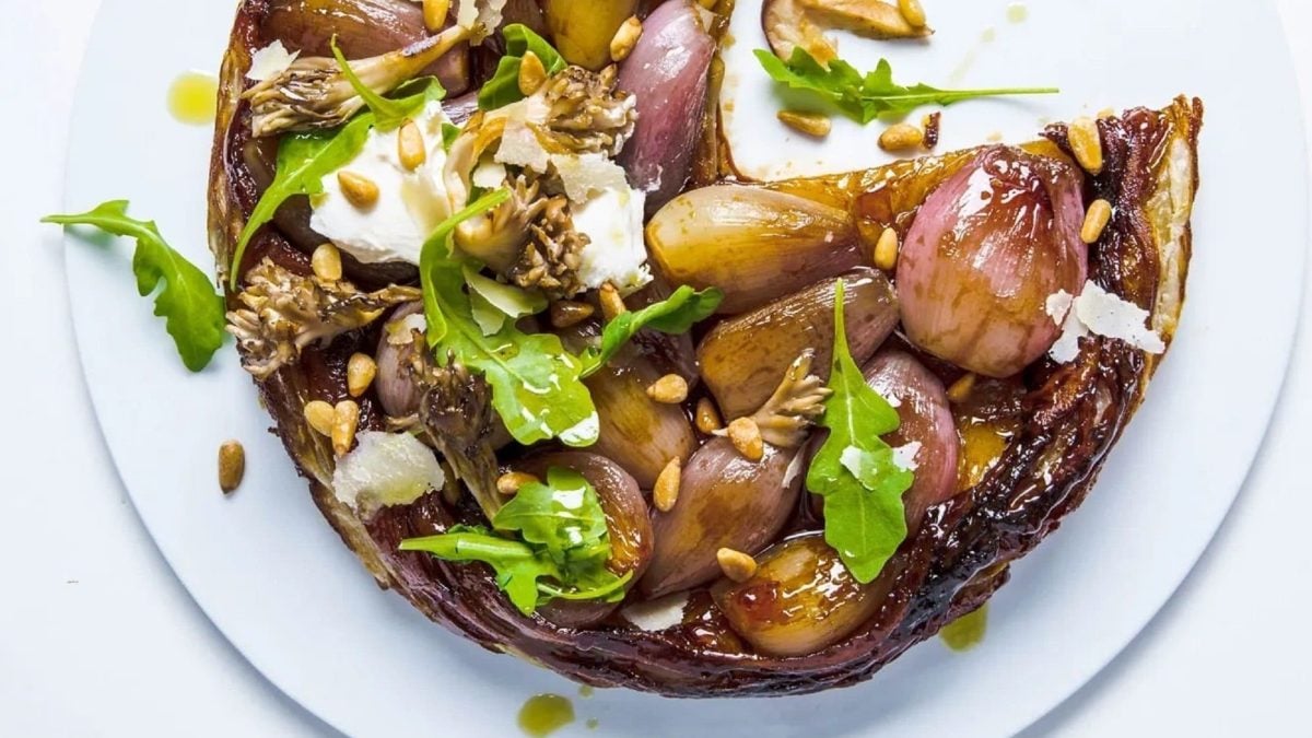 Tarte Tatin mit Balsamico-Schalotte und Burrata auf weißem Teller angeschnitten. Draufsicht.