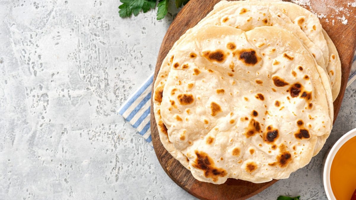 Hausgemachtes Asche-Fladenbrot auf grauem betoniertem Hintergrund, Draufsicht. Frisch gebackenes indisches Flachbrot