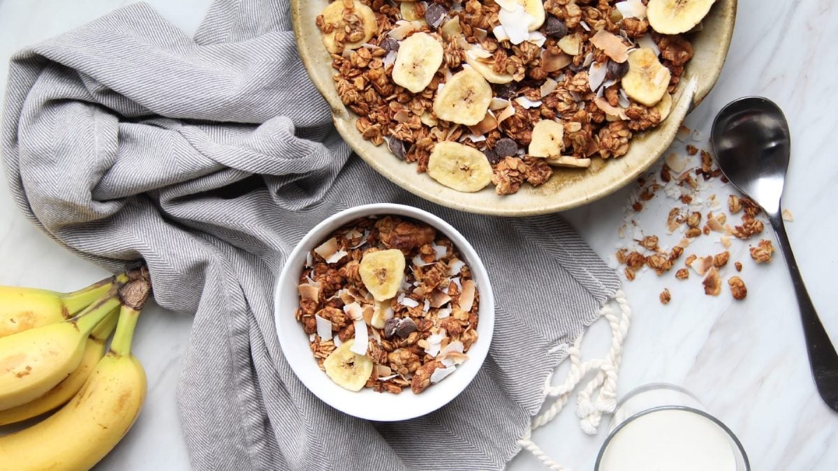 Eine weiße Schale mit dem Bananen-Granola auf hellgrauem Untergrund.