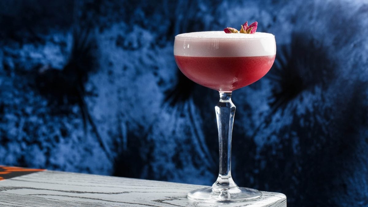 Clover Club Cocktail in Cocktailschale vor dunklem Hintergrund auf Steintisch. Frontalansicht
