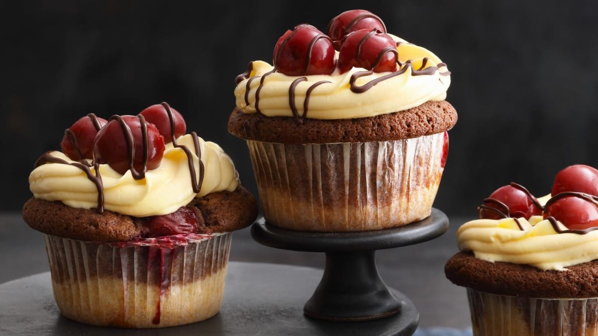 Schwarzer Hintergrund, davor drei Donauwellen-Cupcakes auf Etageren.
