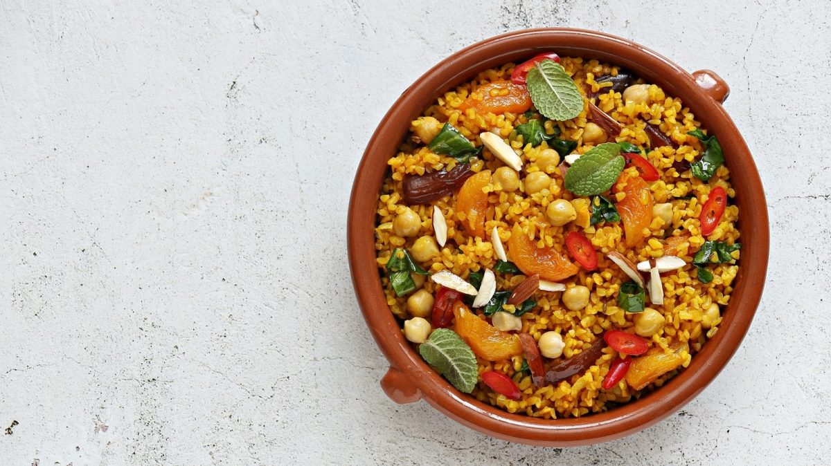 Eine Schüssel Bulgur mit getrocknetem Obst auf einem weißen Tisch.