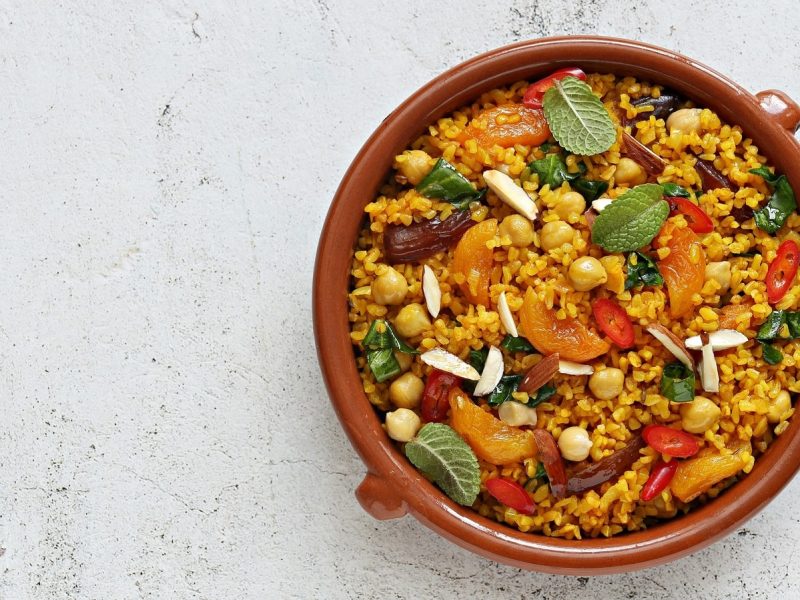 Eine Schüssel Bulgur mit getrocknetem Obst auf einem weißen Tisch.