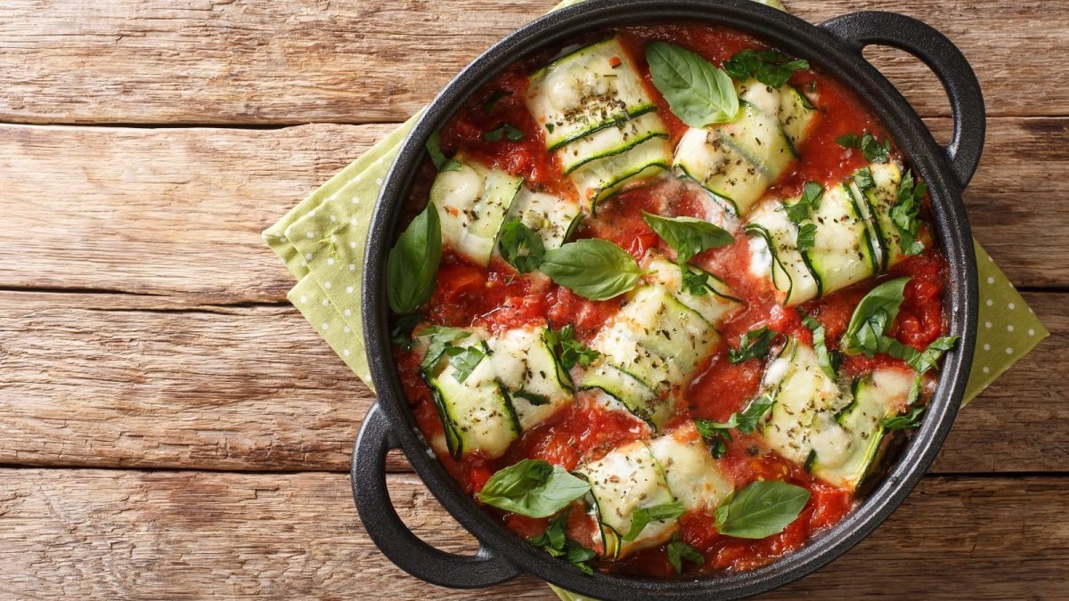 Ein schwarzer Topf mit Involtini di Zucchini auf einem Holztisch.
