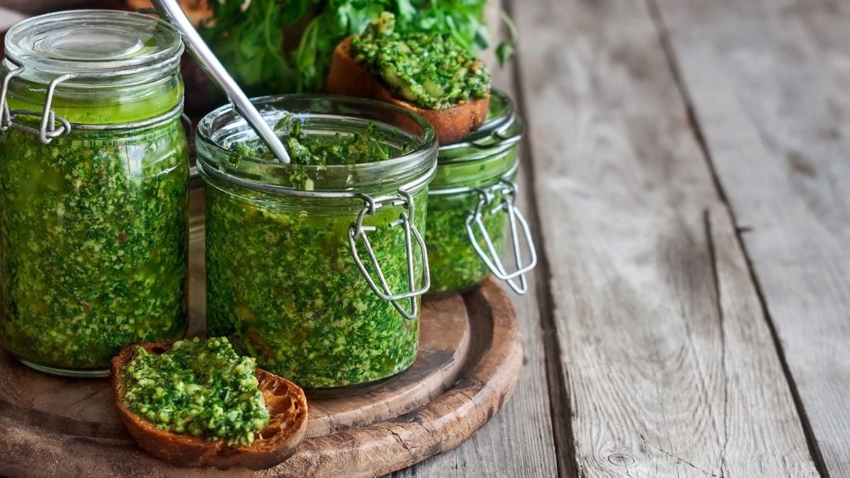 Zwei Gläser mit Koriander-Pesto auf einem Holzbrett.