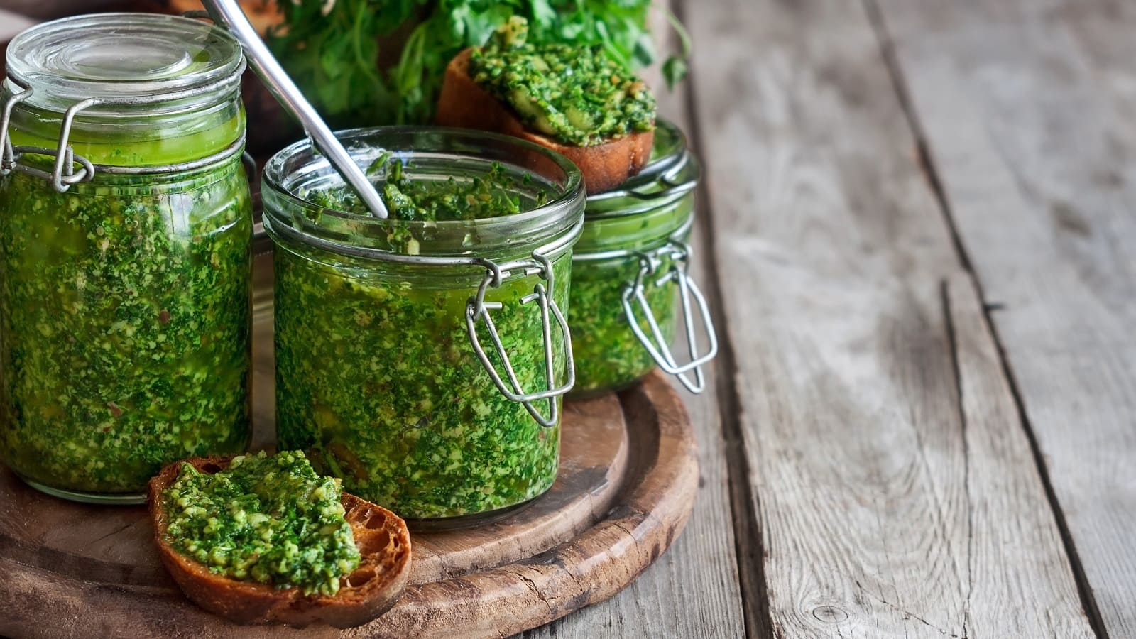 Zwei Gläser mit Koriander-Pesto auf einem Holzbrett.