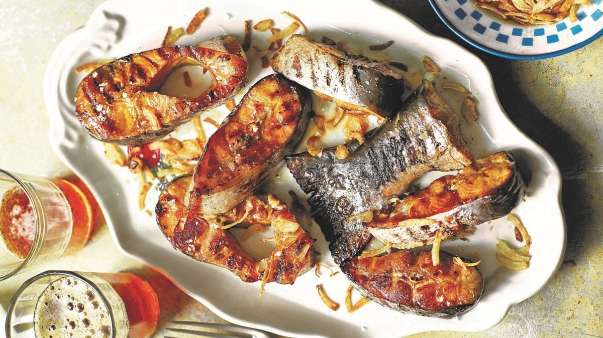 Ein Teller mit gegrillten Wels-Stücken und koreanischem Karottensalat daneben zwei Gläser Bier.