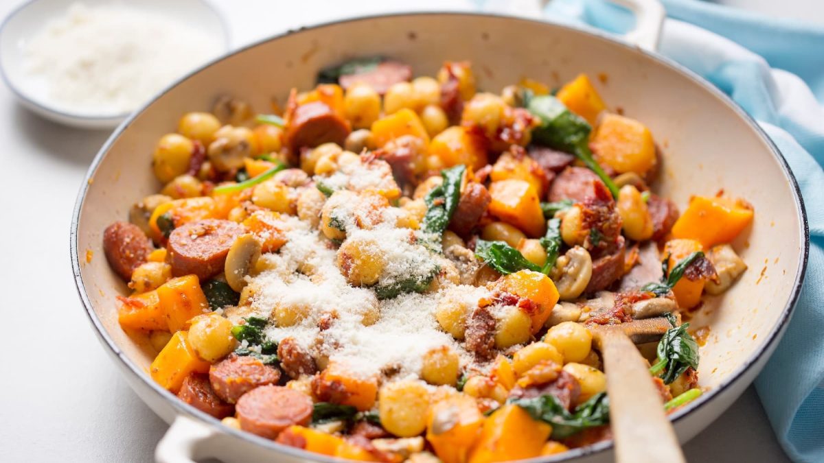 Eine weiße Pfanne mit den Gnocchi auf einem hellen Tisch mit einem blauen Tuch.