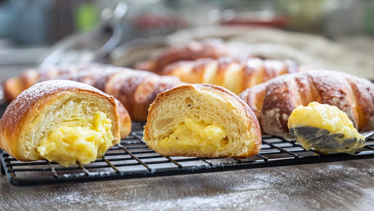 Selbst gemachte Brioche Pudding-Hörnchen auf Backrost. Frontalansicht.