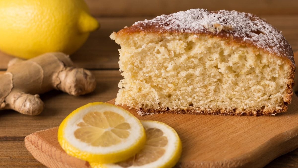 Ein Stück Kuchen auf einem Holzbrett mit Zitronenscheiben und Ingwer.