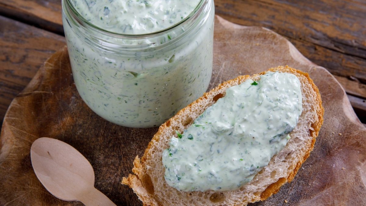 Eine Scheibe Brot mit Bärlauch-Aioli auf einem Holzbrett.