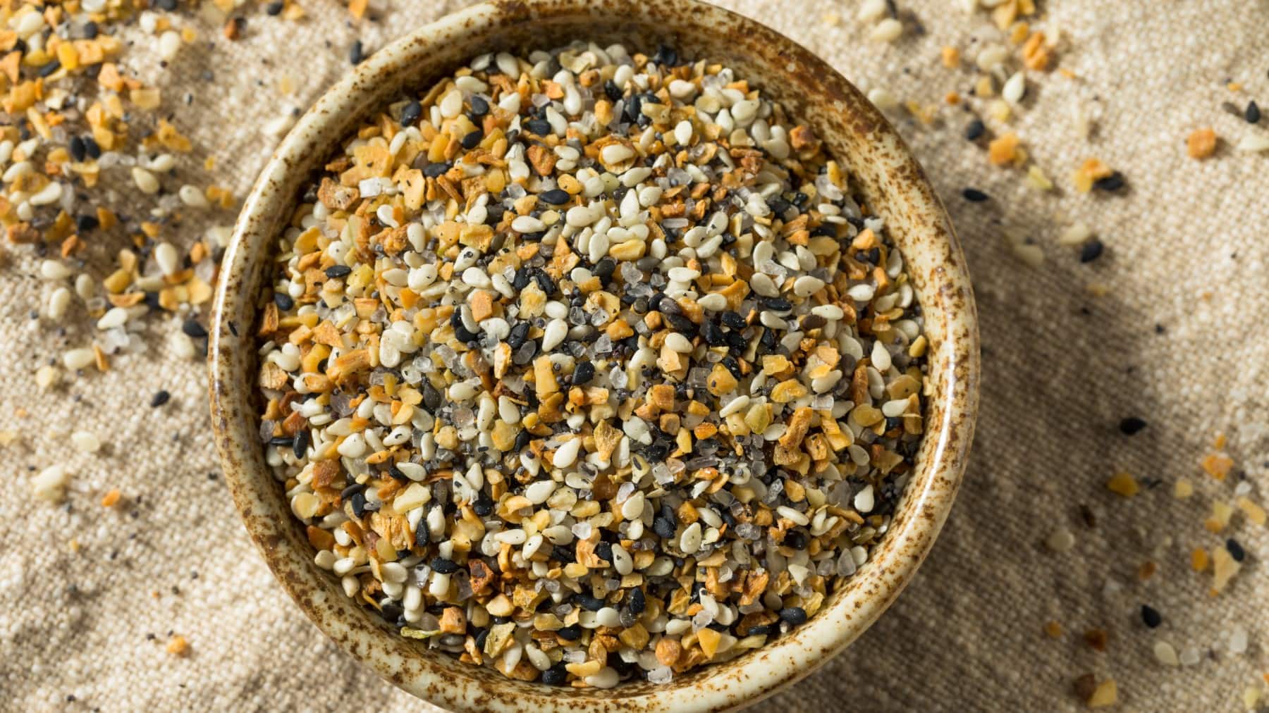 Everything Bagel Seasoning in einer Schüssel vor beigem Hintergrund in der Draufsicht.