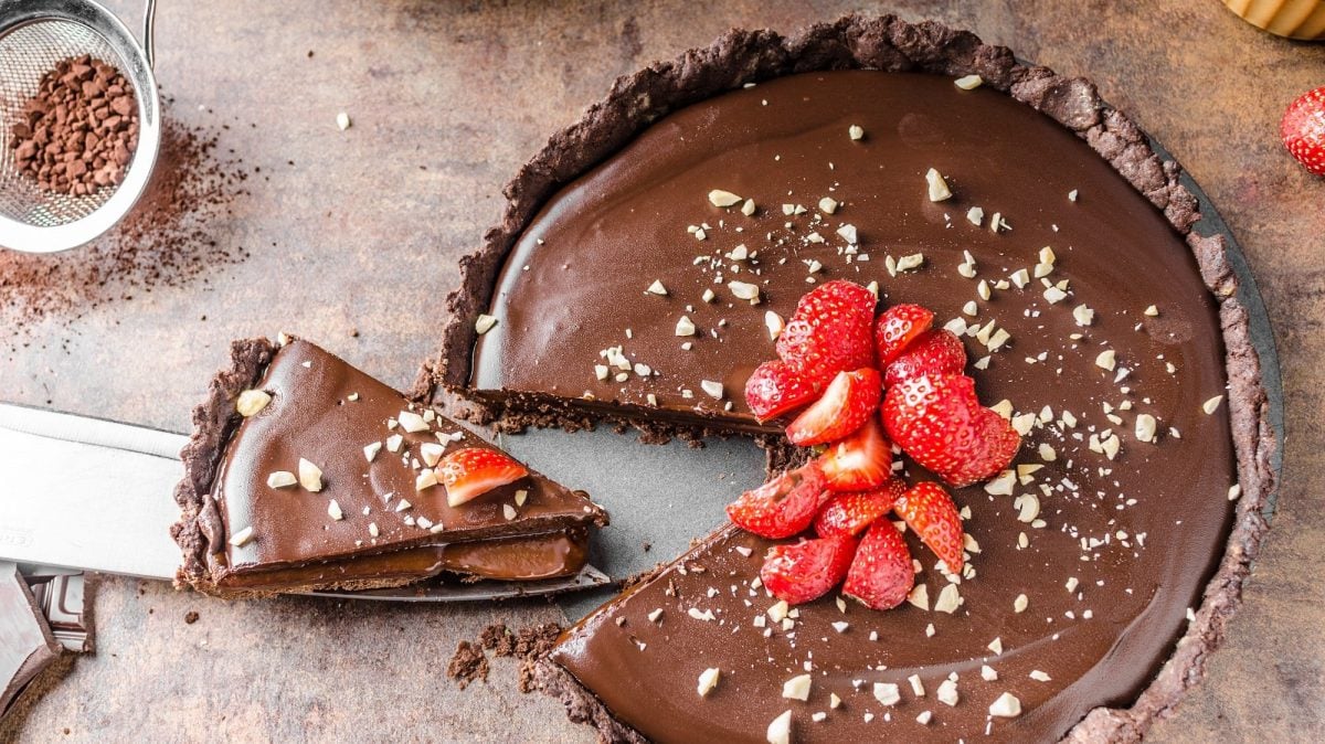 Eine angeschnittene Biscoff-Espresso-Tarte verziert mit Erdbeeren in der Draufsicht.