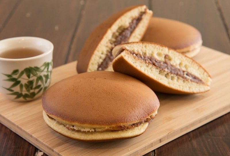 Dorayaki auf Holzbrett mit einer Tasse Tee. Draufsicht.
